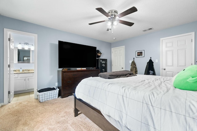 bedroom featuring visible vents, a sink, ceiling fan, light colored carpet, and connected bathroom