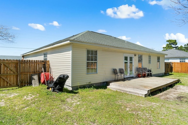 back of property with a deck, a lawn, french doors, and a fenced backyard