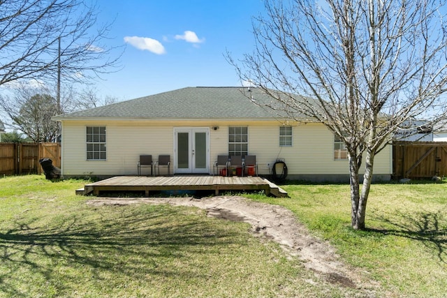 rear view of house with fence, roof with shingles, a yard, french doors, and a deck