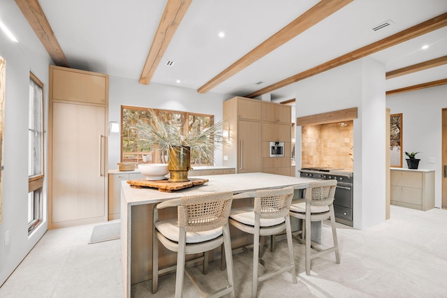 kitchen with high end stove, visible vents, beam ceiling, light brown cabinets, and plenty of natural light