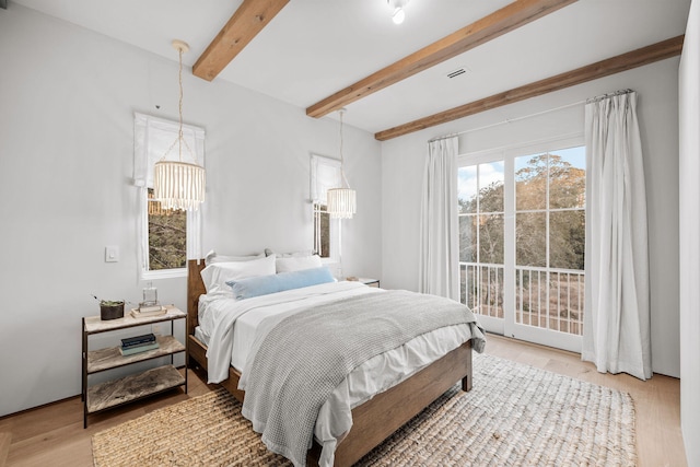 bedroom featuring beamed ceiling, a notable chandelier, and light wood-style floors