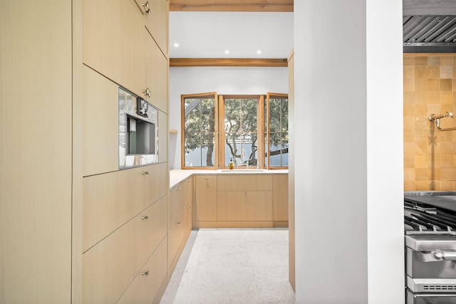 kitchen with stainless steel range with gas stovetop, a sink, light countertops, light brown cabinetry, and recessed lighting
