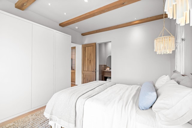 bedroom with wood finished floors and beamed ceiling