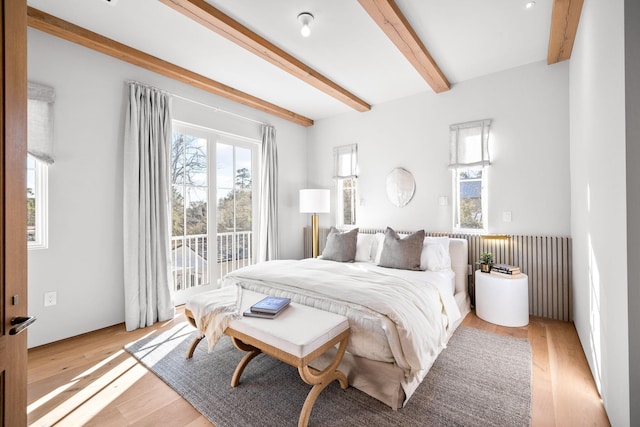 bedroom featuring access to outside, light wood-style floors, radiator, and beam ceiling