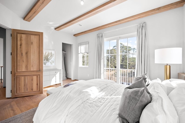 bedroom featuring light wood finished floors, access to outside, multiple windows, and beamed ceiling