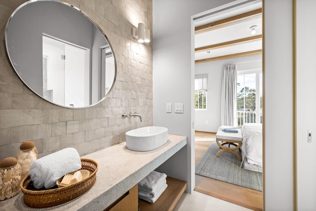 ensuite bathroom with ensuite bath, vanity, backsplash, and wood finished floors