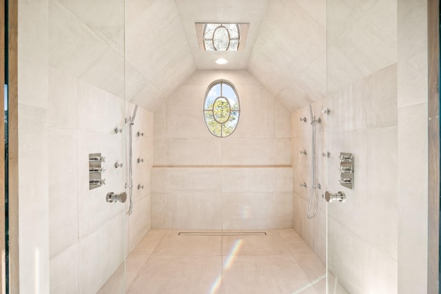 bathroom with a tile shower, tile patterned flooring, and vaulted ceiling