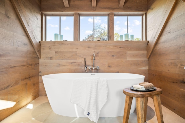 bathroom with a freestanding bath, wooden walls, and a healthy amount of sunlight