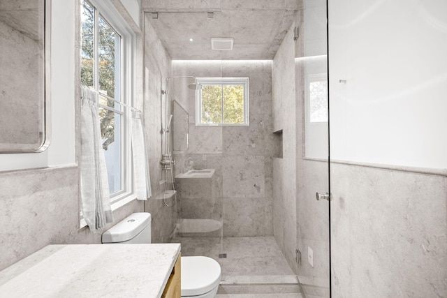 full bath featuring toilet, tiled shower, and vanity