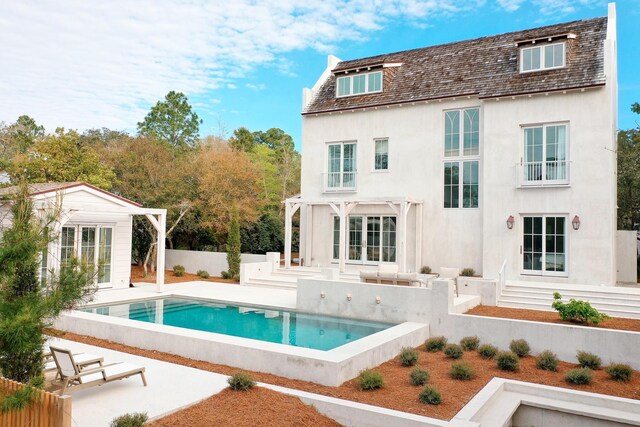rear view of house with an outbuilding, a storage structure, stucco siding, fence, and a fenced in pool