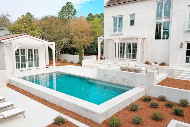 view of swimming pool featuring an outbuilding, an exterior structure, a patio area, fence, and a fenced in pool