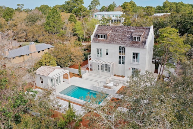 back of house with a pergola, a fenced backyard, stucco siding, an outdoor structure, and an outdoor pool