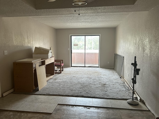 living area featuring carpet floors, baseboards, a textured ceiling, and a textured wall