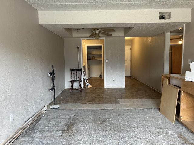 spare room with a tray ceiling, visible vents, a textured wall, and ceiling fan