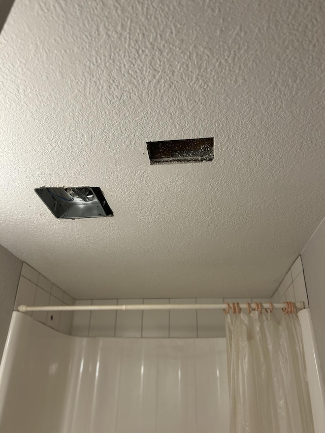 interior details with curtained shower and a textured ceiling