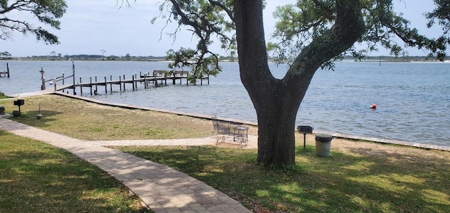 dock area with a lawn and a water view