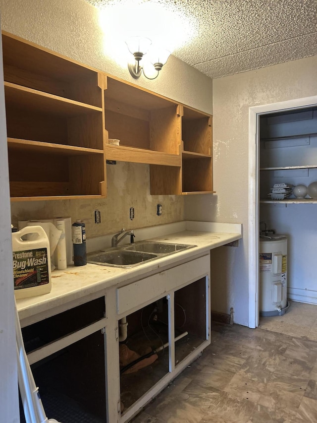 kitchen featuring light countertops, electric water heater, a textured wall, and a sink