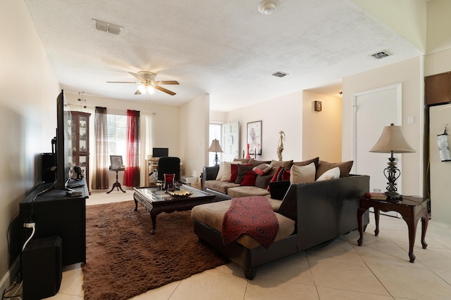 living area featuring visible vents, a textured ceiling, light tile patterned flooring, and a ceiling fan