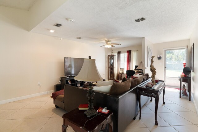 living area with light tile patterned flooring, baseboards, visible vents, and a textured ceiling