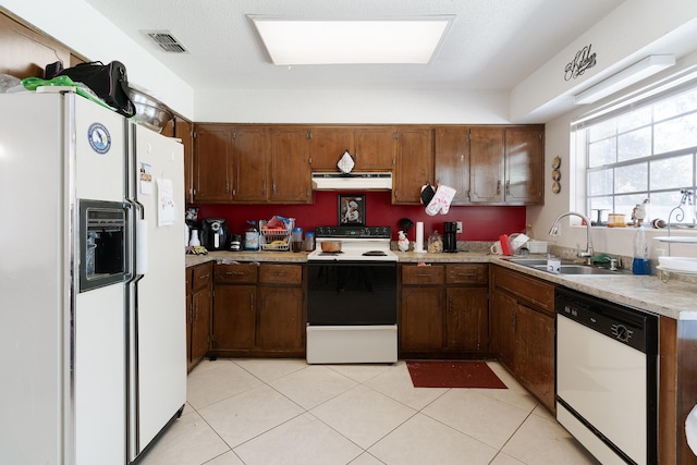 kitchen featuring visible vents, under cabinet range hood, light countertops, white appliances, and a sink