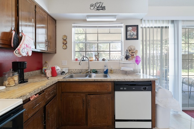 kitchen with stove, a sink, light countertops, and white dishwasher