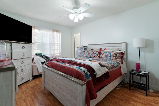 bedroom with a textured ceiling, light wood finished floors, and ceiling fan