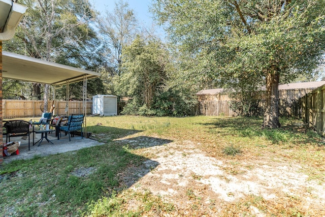 view of yard featuring an outbuilding, a storage unit, a patio area, and a fenced backyard