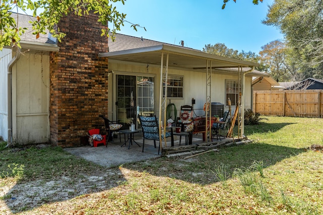 rear view of house featuring fence, roof with shingles, a lawn, a chimney, and a patio