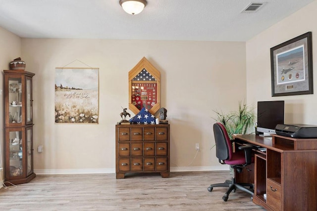 office space featuring baseboards, visible vents, and wood finished floors