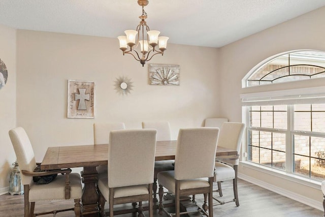 dining area with a notable chandelier, baseboards, and wood finished floors