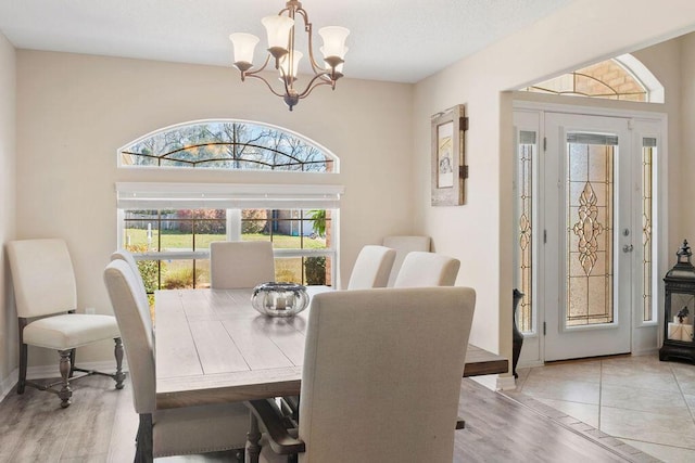 dining area featuring light wood-style floors, baseboards, and a notable chandelier