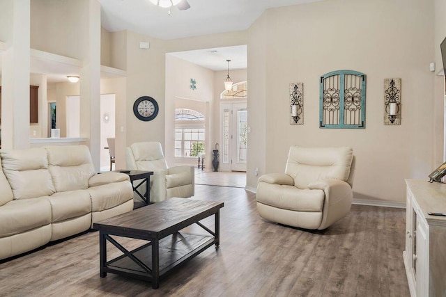 living room featuring wood finished floors, a towering ceiling, and baseboards