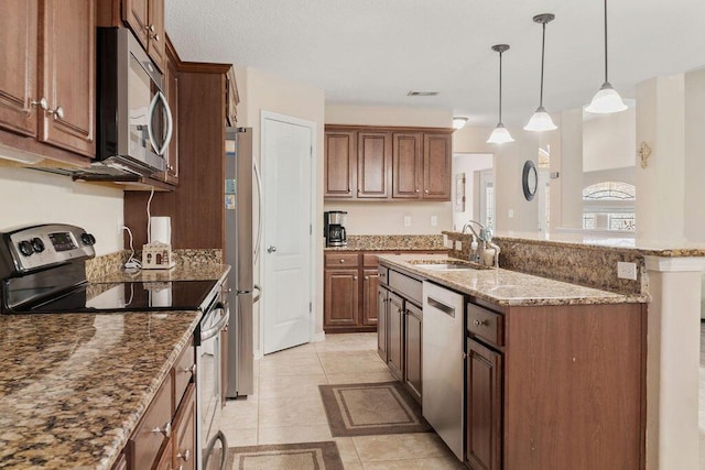 kitchen with light stone counters, decorative light fixtures, stainless steel appliances, visible vents, and a sink