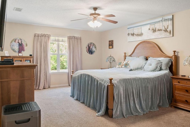 bedroom with a textured ceiling, light colored carpet, a ceiling fan, baseboards, and visible vents