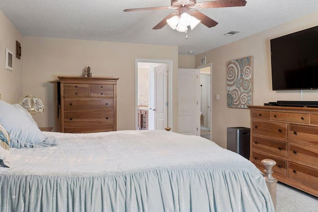 carpeted bedroom with a textured ceiling, ceiling fan, ensuite bath, and visible vents