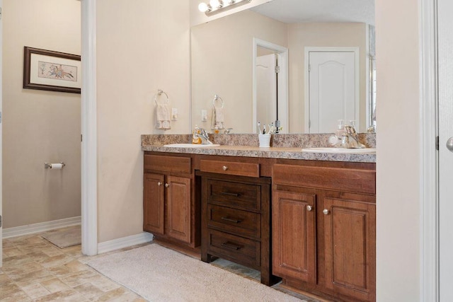 bathroom with double vanity, baseboards, and a sink