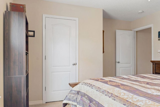 carpeted bedroom featuring a textured ceiling and baseboards