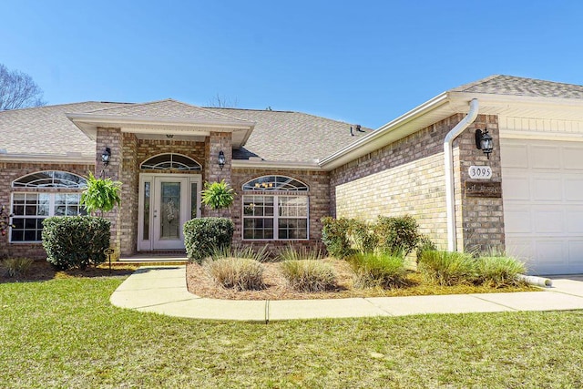 property entrance featuring a garage, brick siding, and a shingled roof