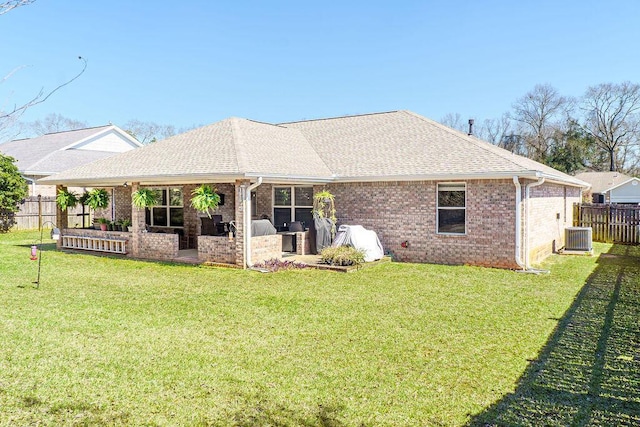 back of property featuring roof with shingles, a lawn, and fence