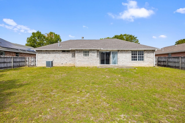 rear view of house featuring cooling unit, a fenced backyard, a yard, and brick siding