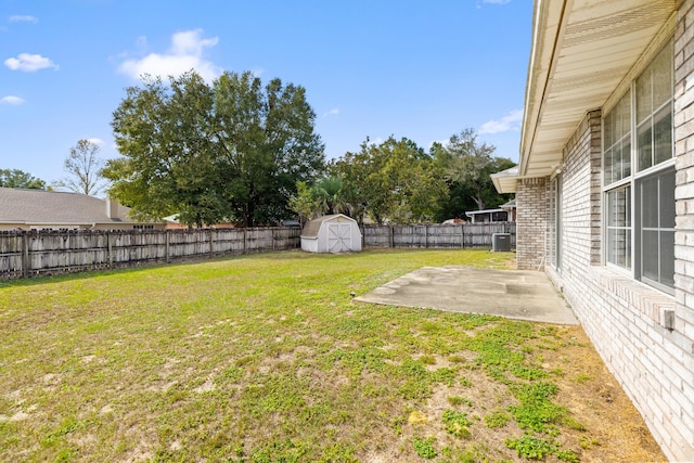 view of yard with a storage shed, a fenced backyard, an outbuilding, cooling unit, and a patio area