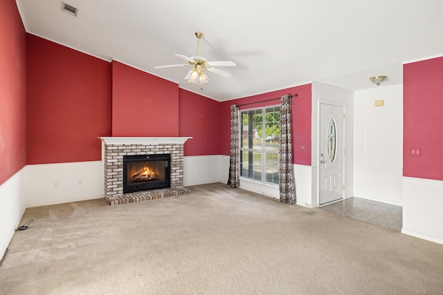 unfurnished living room featuring lofted ceiling, carpet floors, a fireplace, visible vents, and a ceiling fan