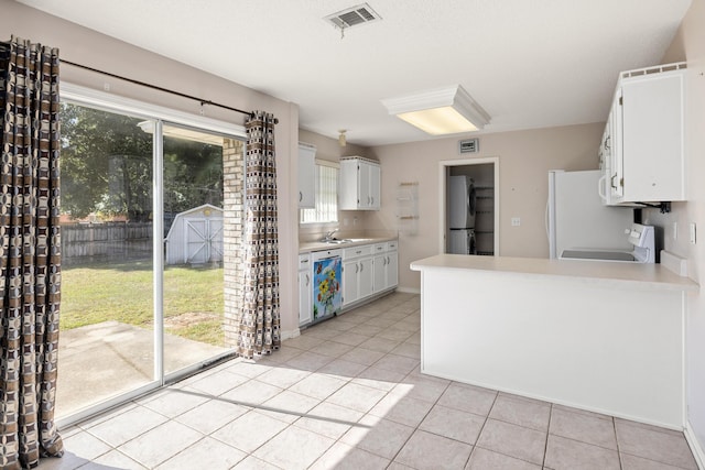 kitchen featuring light tile patterned floors, dishwashing machine, stove, refrigerator, and light countertops