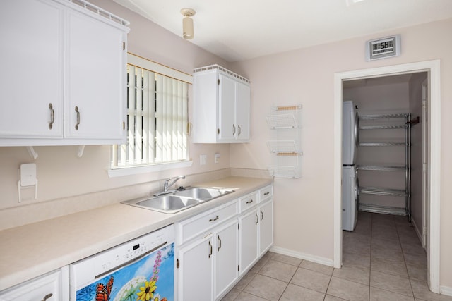 kitchen with light tile patterned floors, white dishwasher, white cabinetry, and a sink