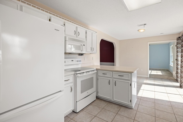 kitchen with arched walkways, light tile patterned floors, visible vents, white appliances, and a peninsula