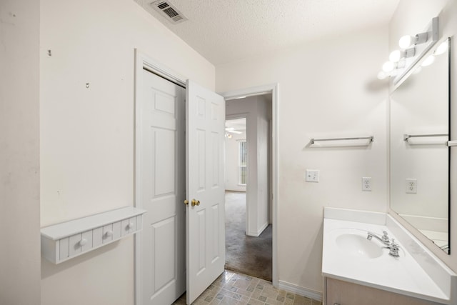 bathroom featuring baseboards, visible vents, a textured ceiling, and vanity