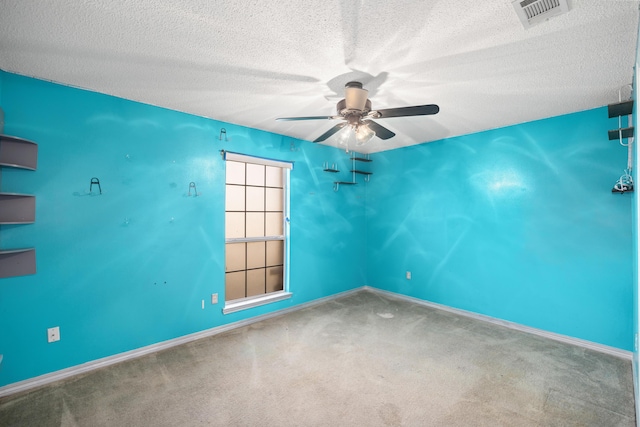 carpeted empty room with a ceiling fan, visible vents, a textured ceiling, and baseboards