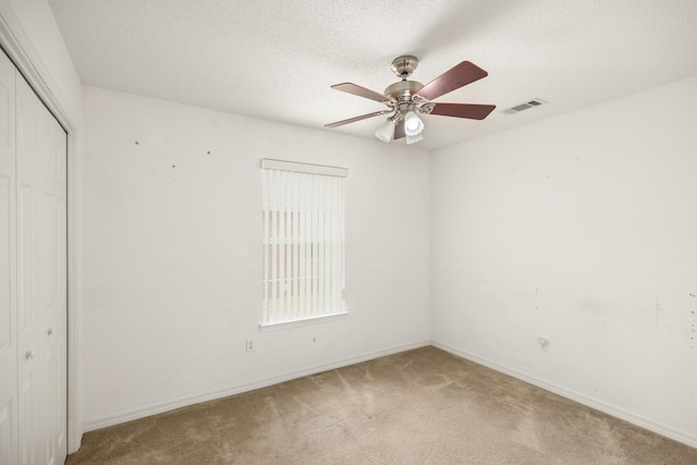 empty room featuring baseboards, visible vents, a ceiling fan, a textured ceiling, and carpet flooring