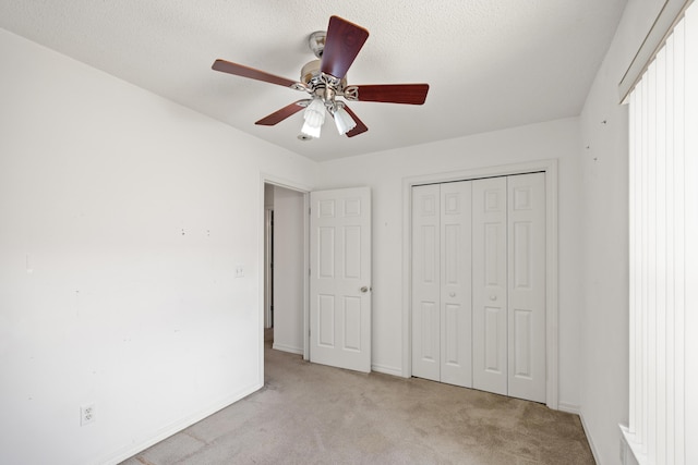 unfurnished bedroom with a textured ceiling, baseboards, a closet, and light colored carpet