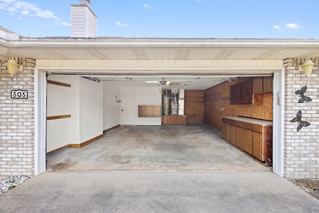 garage featuring a garage door opener, concrete driveway, and heating unit